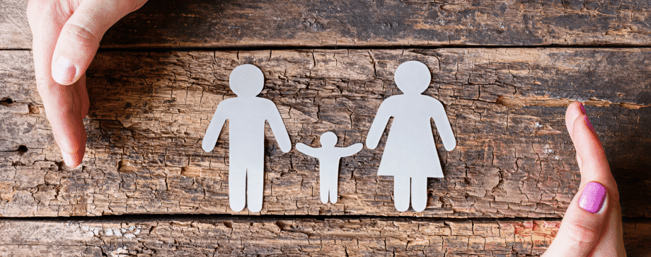 Paper family with protective hands on wood.